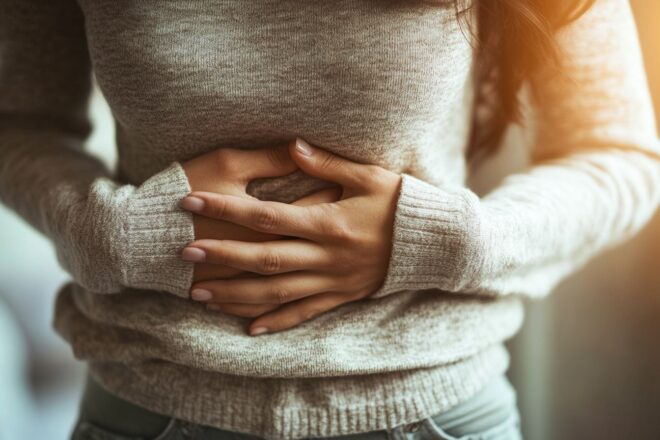 Une personne ressent une gêne intense au niveau de l'estomac et montre des signes de malaise facial.
