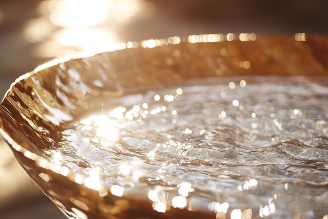 Gros plan d'un grand bol rempli d'eau claire et scintillante reflétant une lumière douce du soleil.