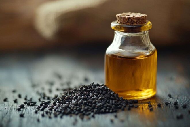 Gros plan d une petite bouteille d huile de kalonji avec des graines noires